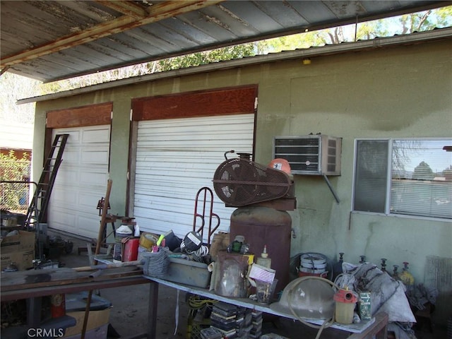 exterior space with a wall unit AC, a garage, and stucco siding