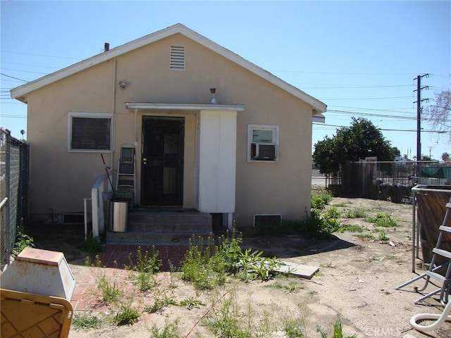 back of house featuring entry steps, fence, and stucco siding