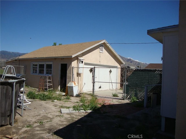 back of property featuring an outbuilding, fence, a mountain view, and stucco siding