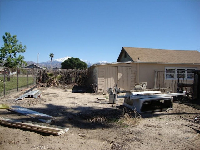 view of yard with an outdoor structure, fence, a mountain view, and a shed