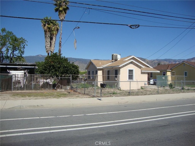 view of front of property with a mountain view, central AC, and a fenced front yard