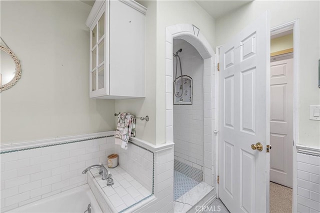 full bathroom with tiled shower, tile walls, a bath, and wainscoting