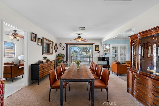 dining area with light colored carpet, visible vents, and ceiling fan