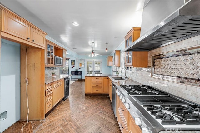 kitchen featuring beverage cooler, a sink, stainless steel appliances, a peninsula, and wall chimney range hood