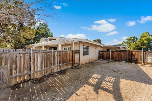 view of side of property with fence, a pergola, and stucco siding