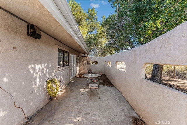 view of property exterior with stucco siding, fence, and a patio area