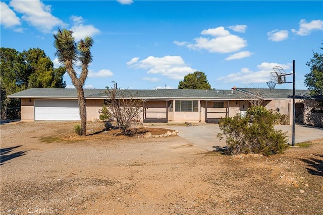 single story home with stucco siding, a garage, and dirt driveway