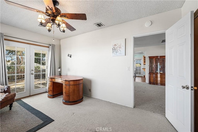 interior space featuring a ceiling fan, visible vents, french doors, a textured ceiling, and carpet flooring