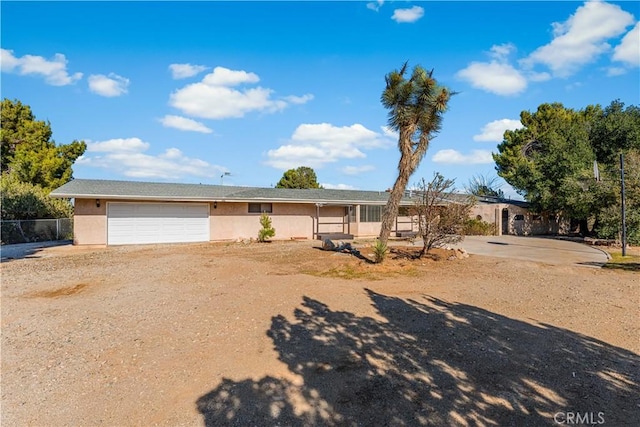 ranch-style house featuring an attached garage, fence, driveway, and stucco siding