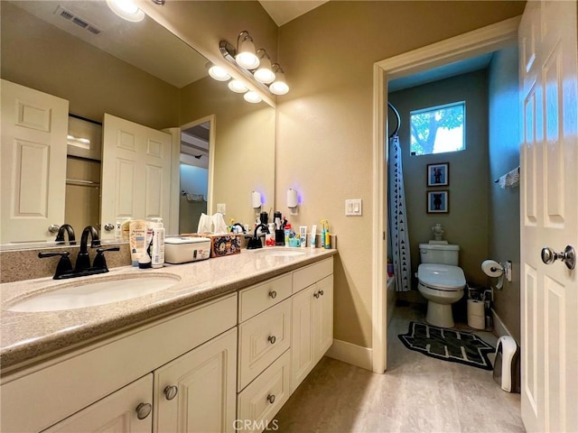 bathroom with double vanity, visible vents, toilet, and a sink