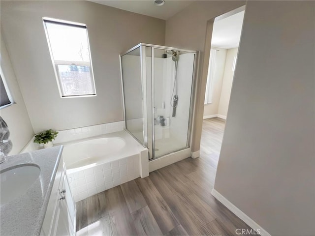 full bath featuring vanity, wood finished floors, baseboards, a shower stall, and a bath