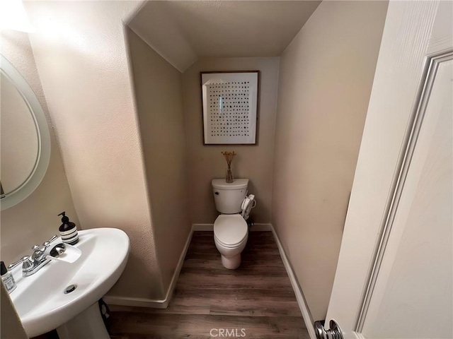 bathroom featuring a sink, baseboards, toilet, and wood finished floors