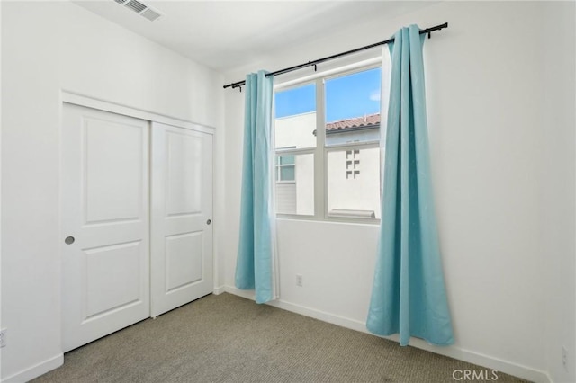 unfurnished bedroom with carpet, visible vents, a closet, and baseboards