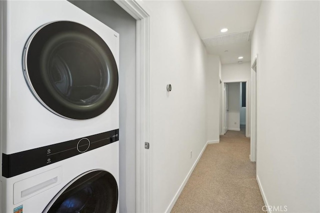 clothes washing area with baseboards, laundry area, recessed lighting, light carpet, and stacked washer / dryer