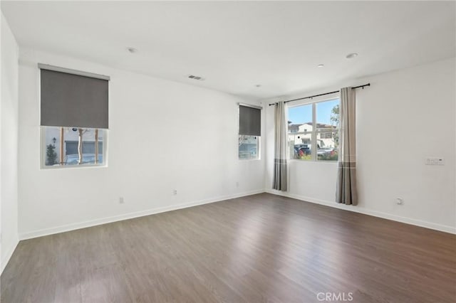 spare room featuring visible vents, baseboards, and wood finished floors