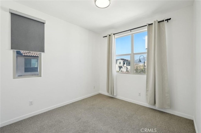 carpeted spare room featuring baseboards