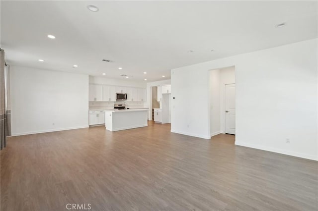 unfurnished living room featuring recessed lighting, baseboards, and light wood finished floors