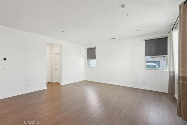 unfurnished room with visible vents, wood finished floors, and baseboards