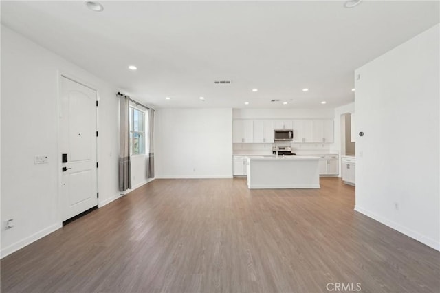 unfurnished living room featuring recessed lighting, wood finished floors, visible vents, and baseboards