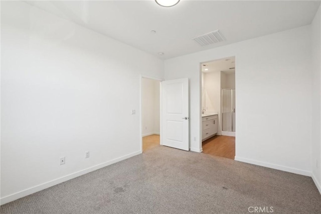 unfurnished bedroom with light colored carpet, visible vents, ensuite bathroom, and baseboards