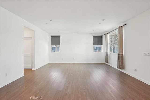 spare room with baseboards and wood finished floors