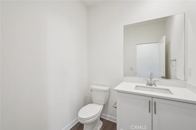 bathroom featuring vanity, toilet, wood finished floors, and baseboards