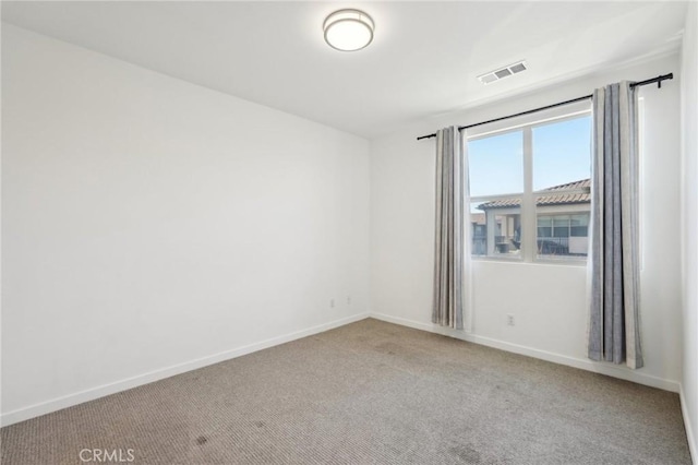 empty room with carpet, visible vents, and baseboards