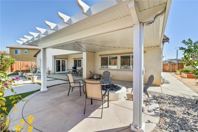 view of patio with french doors, a fire pit, and fence