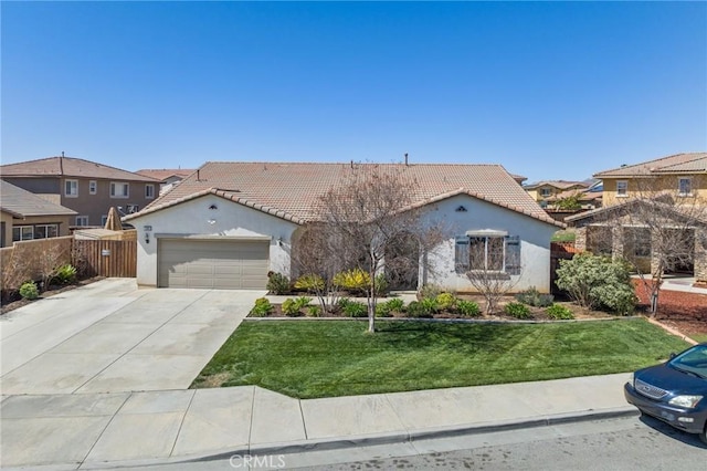 mediterranean / spanish-style house featuring fence, an attached garage, stucco siding, a front lawn, and a tiled roof