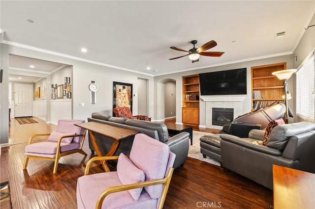 living area with visible vents, arched walkways, dark wood finished floors, and a tiled fireplace