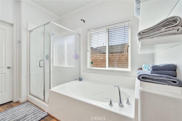 bathroom with wood finished floors, ornamental molding, a shower stall, and a bath