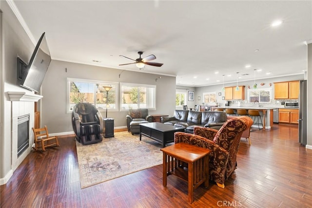 living area with crown molding, baseboards, recessed lighting, a fireplace, and dark wood-style floors