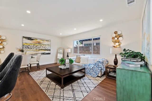 living room with recessed lighting, visible vents, baseboards, and wood finished floors