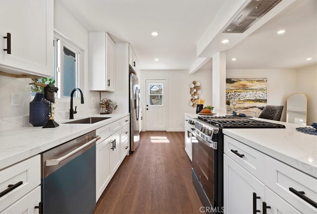 kitchen with light stone countertops, dark wood finished floors, stainless steel appliances, white cabinetry, and a sink