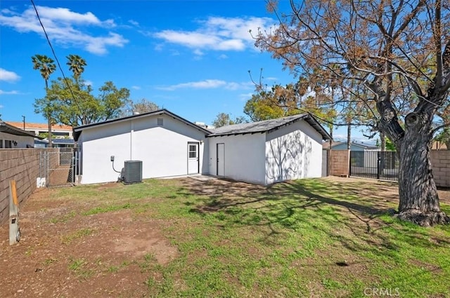 exterior space with stucco siding, a lawn, a gate, a fenced backyard, and central AC unit