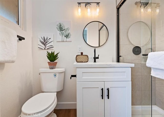 bathroom featuring a tile shower, toilet, vanity, and baseboards