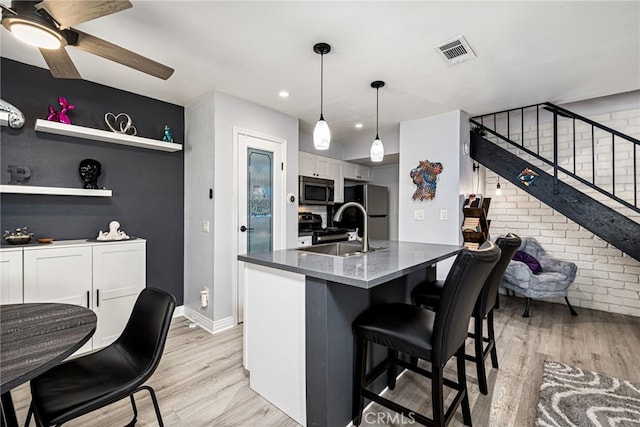 kitchen featuring stainless steel microwave, light wood-style floors, visible vents, and freestanding refrigerator