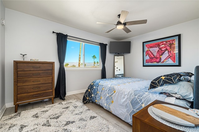 bedroom with a ceiling fan, wood finished floors, and baseboards