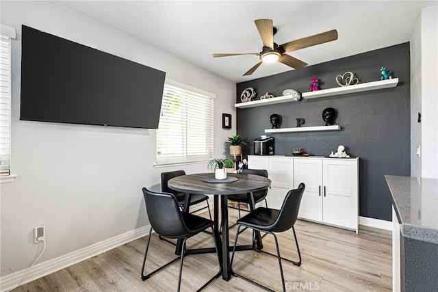 dining space featuring a ceiling fan, light wood-type flooring, and baseboards