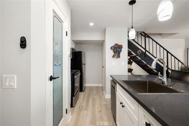 kitchen featuring dark countertops, a sink, dishwasher, white cabinetry, and range