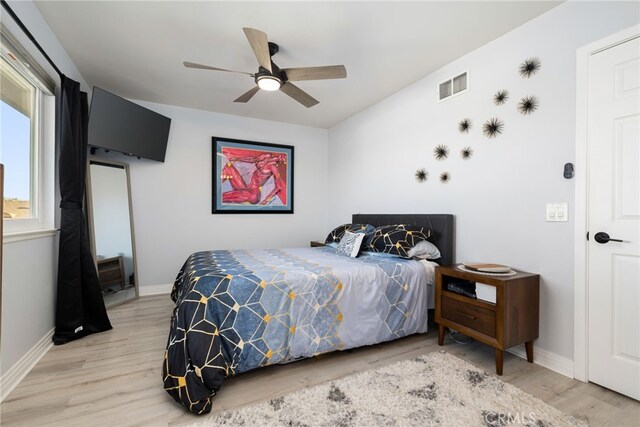 bedroom featuring a ceiling fan, wood finished floors, visible vents, and baseboards