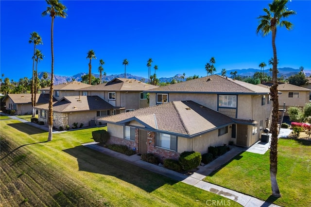 view of front of house featuring a mountain view, a residential view, cooling unit, roof with shingles, and a front yard