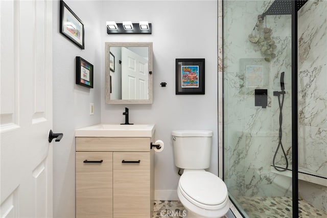 bathroom featuring a marble finish shower, toilet, vanity, and baseboards