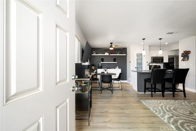 interior space featuring visible vents, ceiling fan, baseboards, and light wood-style floors