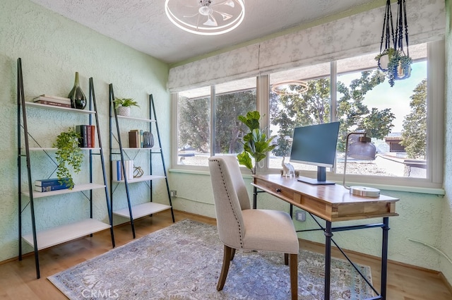 office area featuring a textured ceiling, wood finished floors, and a textured wall