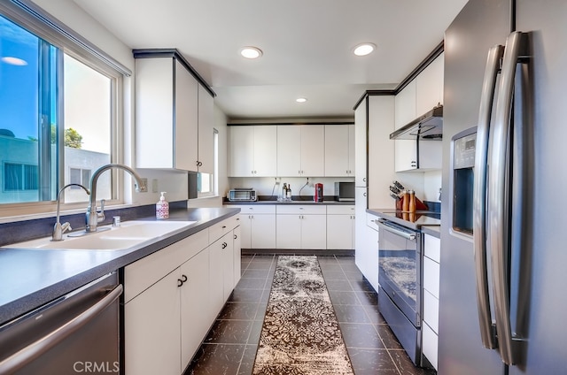 kitchen with under cabinet range hood, recessed lighting, stainless steel appliances, white cabinetry, and a sink