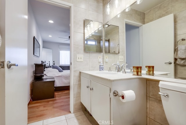 bathroom featuring vanity, ceiling fan, tile walls, toilet, and tile patterned floors