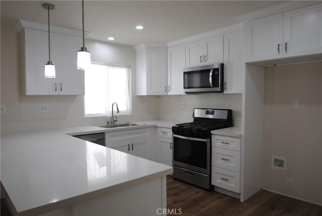 kitchen with a sink, a peninsula, white cabinets, stainless steel appliances, and dark wood-style flooring