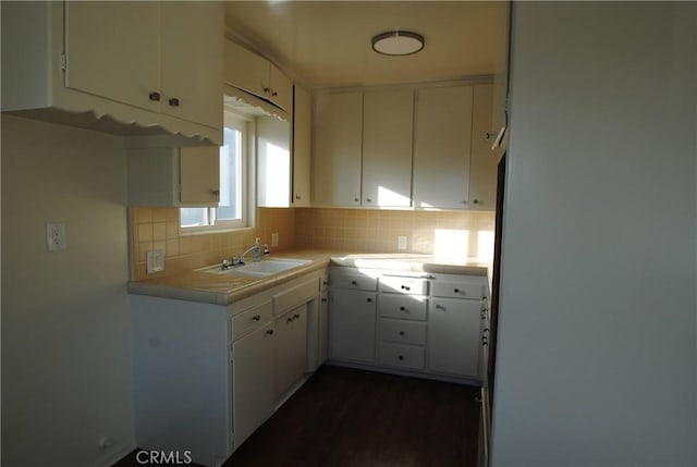 kitchen featuring decorative backsplash, dark wood-style flooring, white cabinetry, and a sink