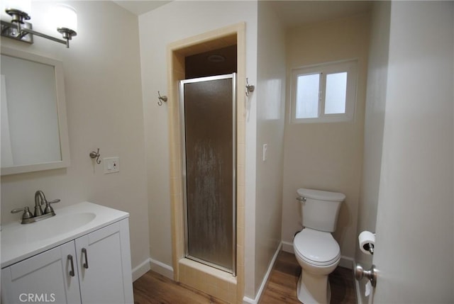 bathroom with vanity, wood finished floors, baseboards, a shower stall, and toilet